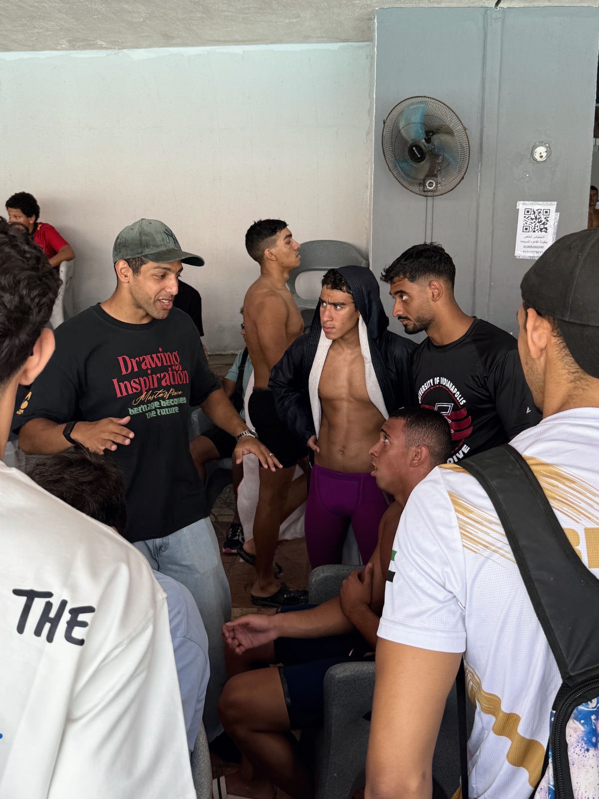 Head coach Omar Elewa explaining something to a group of SWEEP swimmers between races