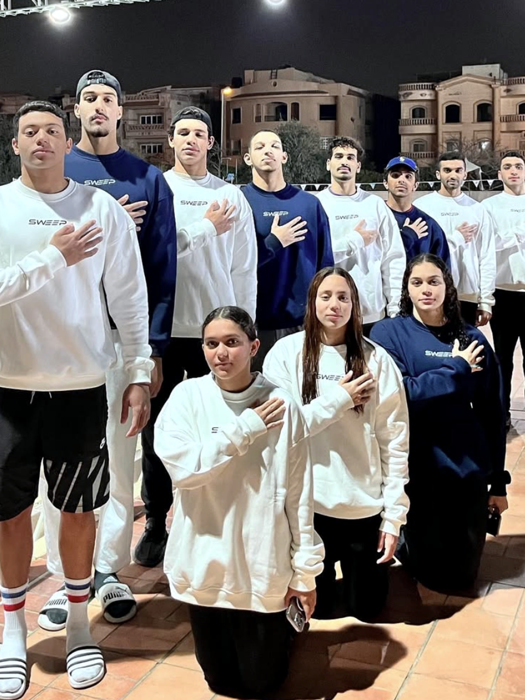 The SWEEP squad in club sweatshirts at night, hands on hearts