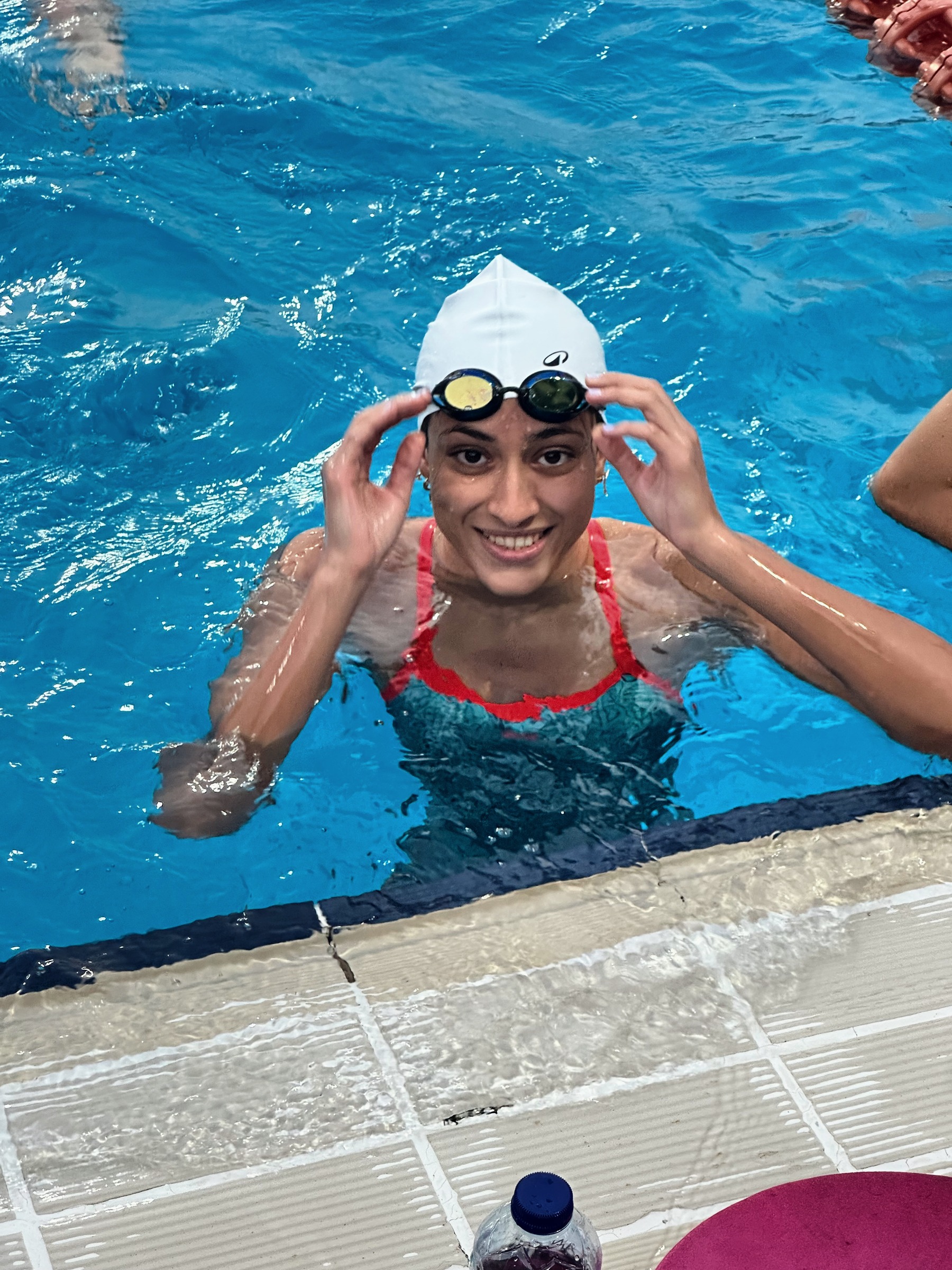 A SWEEP swimmer at the wall lifting her goggles, grinning